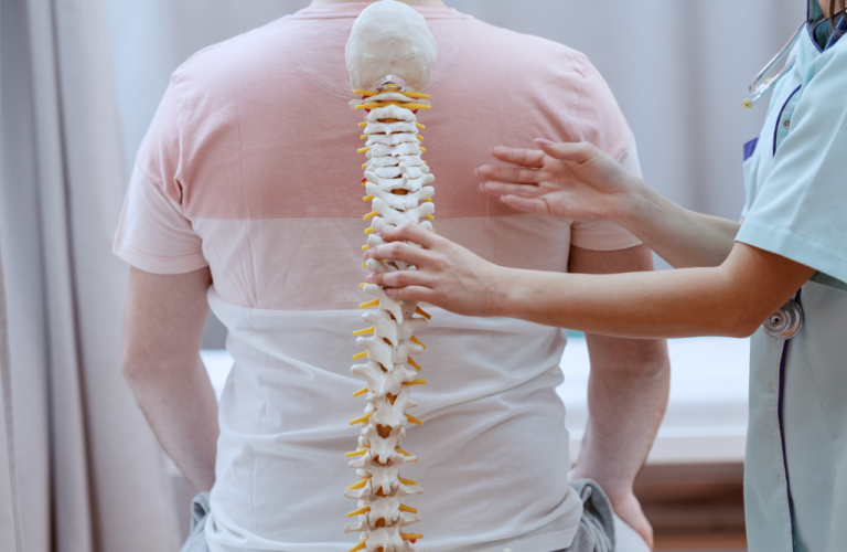 Persona de espalda junto a la columna vertebral.