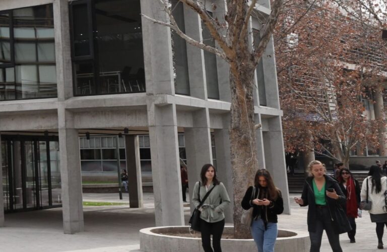 Grupo de personas caminando fuera de la facultad de pedagogía UC.