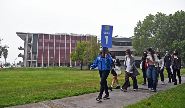 Grupo de estudiantes de enseñanza media caminando por el campus, guiados por una embajadora UC